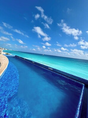 A clear blue pool with a view of the ocean and a distant shoreline. - Beautiful Caribbean Spectacular Ocean View (Cancún)