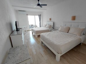 A hotel room with two beds, a ceiling fan, a TV, and a view of the outside. - Beautiful Caribbean Spectacular Ocean View (Cancún)
