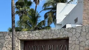 A stone wall with the text "CANCUN PLAZA" and a landscaped area with various plants. - Ocean View Suite 2 Cancun (Cancún)