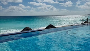 A clear blue pool with a view of the ocean and a cloudy sky. - Beautiful Caribbean Spectacular Ocean View (Cancún)