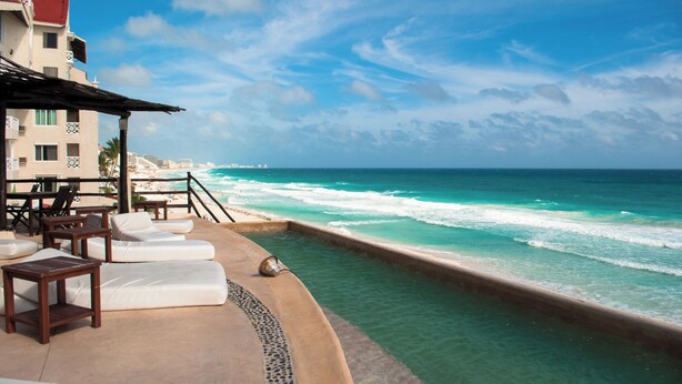 A beachfront hotel with a pool, lounge chairs, and a view of the ocean. - Ocean View Suite 2 Cancun (Cancún)