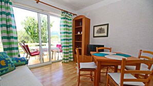 Ein gemütliches Zimmer mit einem Holzesstisch, Stühlen, einer Couch und einem Bücherregal.