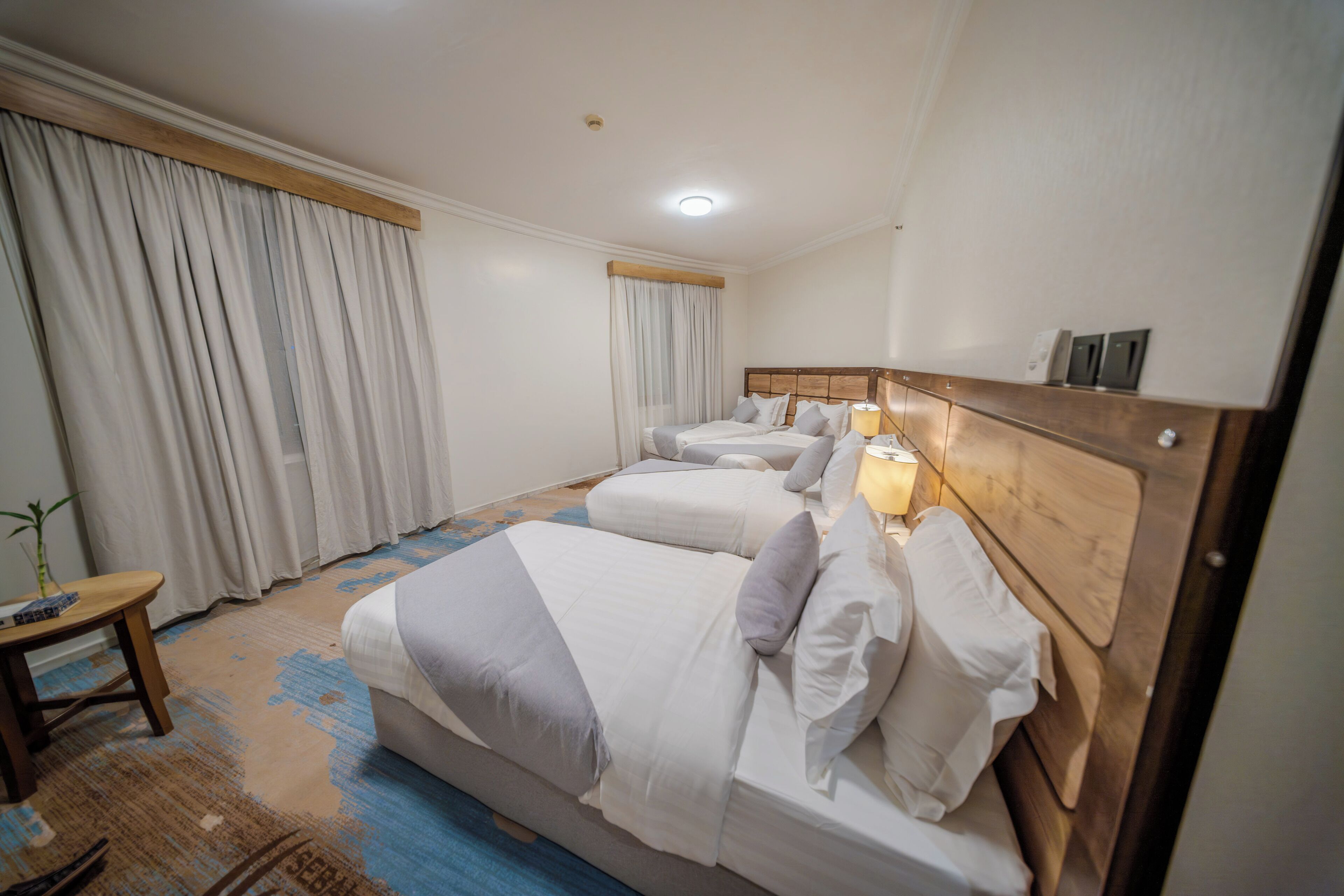 A hotel room with a large bed, a bedside table, and a lamp.