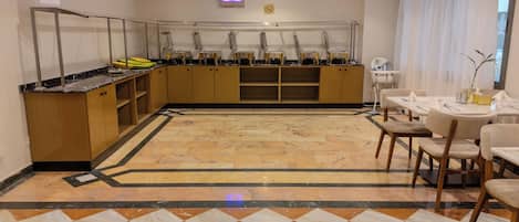 Un hall d’hôtel doté d’un sol en marbre, de meubles en bois, d’un espace buffet et d’un coin salon avec des tables et des chaises.