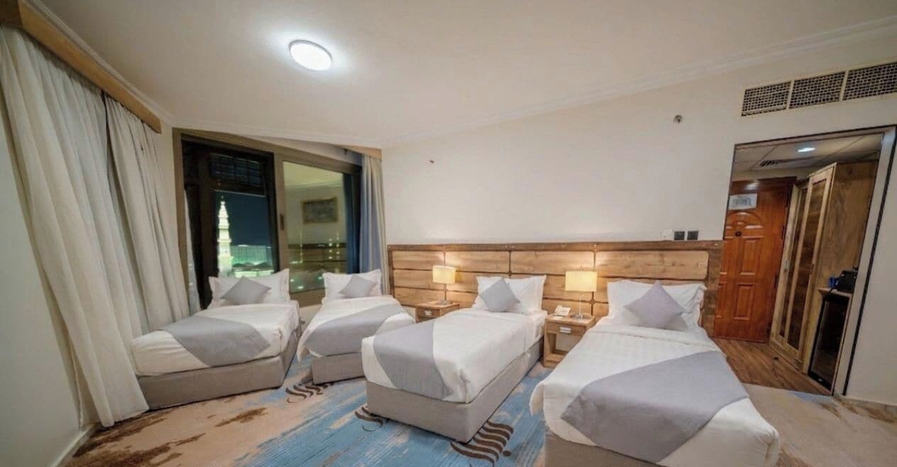 A hotel room with two beds, a wooden headboard, bedside lamps, and a view of a building through a window.