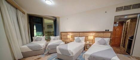 A hotel room with two beds, a wooden headboard, bedside lamps, and a view of a building through a window.
