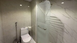 Une salle de bain moderne avec une douche à parois de verre, des toilettes et un bidet.