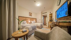 Une chambre d’hôtel avec deux lits, un bureau, une télévision et une horloge au mur.