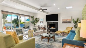 Una sala de estar moderna con chimenea, asientos cómodos y un gran ventanal con vista a una piscina.