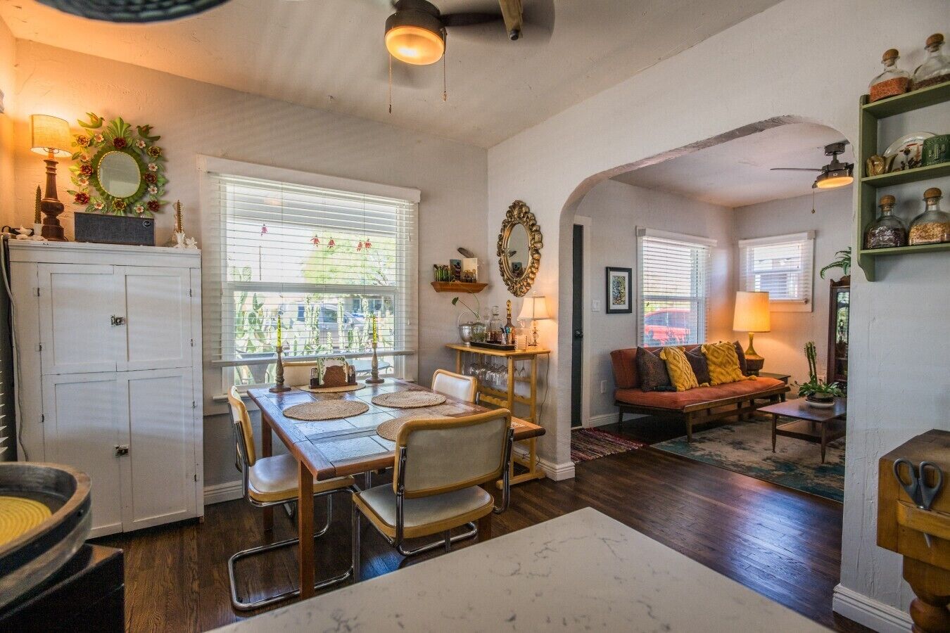 A dining area with a table and chairs, a kitchen with cabinets, and a living room with a sofa.