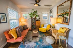 A cozy living room with a red sofa, yellow armchairs, a coffee table, and a large mirror.