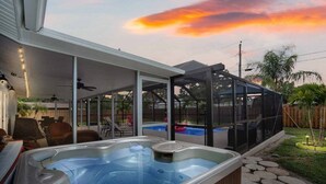 Un espacio al aire libre techado con jacuzzi, piscina y patio con sillas y una mesa.
