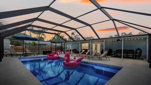 Una piscina interior con techo de cristal, sillones de descanso y vistas a la puesta de sol.