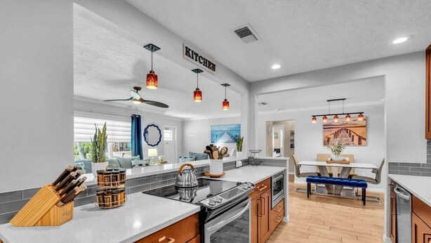 Una cocina moderna con una isla central, armarios de madera e iluminación colgante.