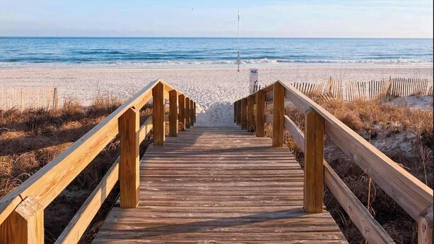 Ein hölzerner Gehweg führt zu einem Strand mit freiem Blick auf den Ozean.