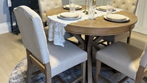 A dining area with a round wooden table, four upholstered chairs, and a lace tablecloth. - Newly renovated 2 bedroom home located near the waterfront and Carnegie Library! (Munhall)