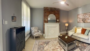 A living room with a fireplace, a sofa, a coffee table, and a rug. - Newly renovated 2 bedroom home located near the waterfront and Carnegie Library! (Munhall)