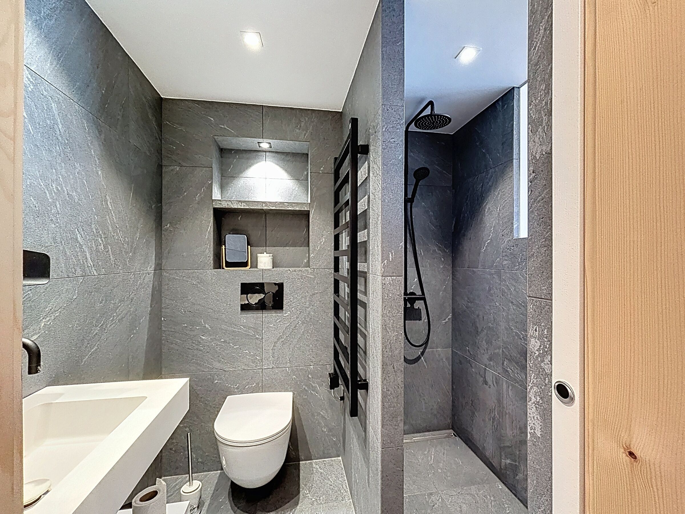 A modern bathroom with a white toilet, a bathtub, and a shower area.