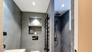 Un baño moderno con inodoro blanco, bañera y zona de ducha.