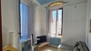 En stue med sofa, fjernsyn og et lille bord.