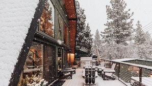 A snow-covered deck with outdoor seating and a building with large windows.