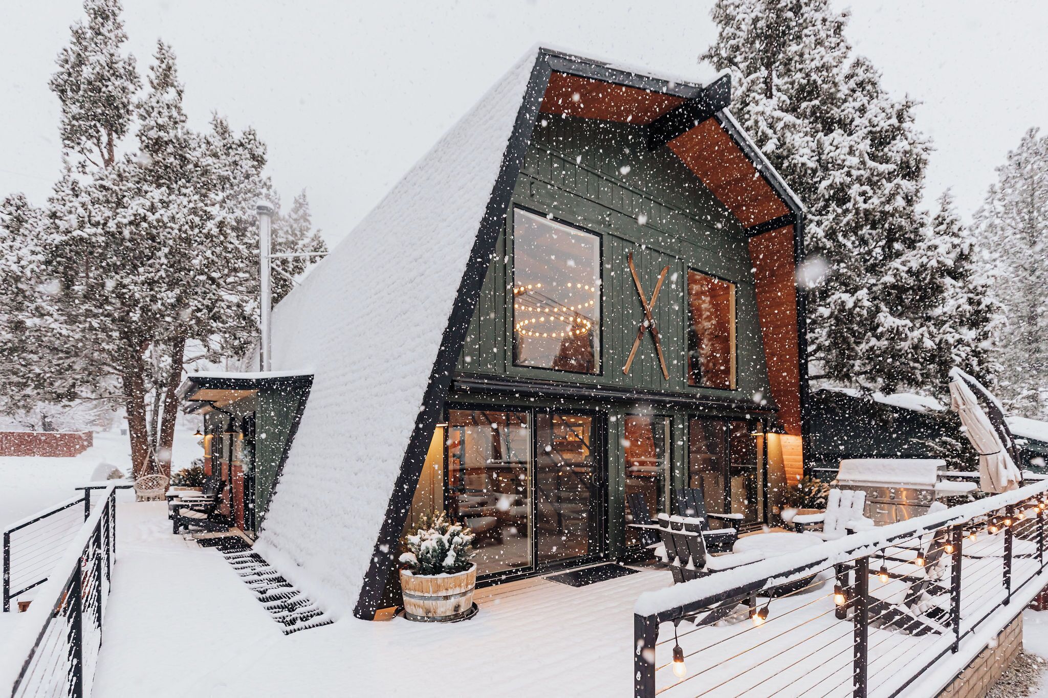 A modern house with a steep roof, large windows, and a deck.