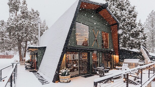 A modern house with a steep roof, large windows, and a deck.