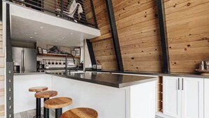 A modern kitchen with a central island, white cabinetry, and a wooden ceiling.