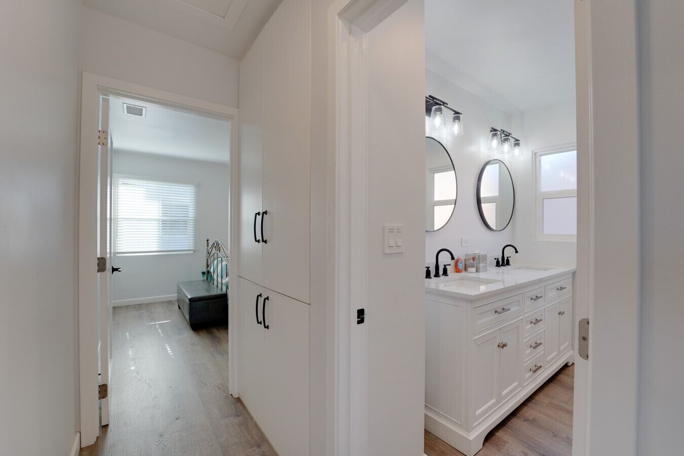 Un baño moderno con lavamanos doble, tocador y dos espejos grandes.