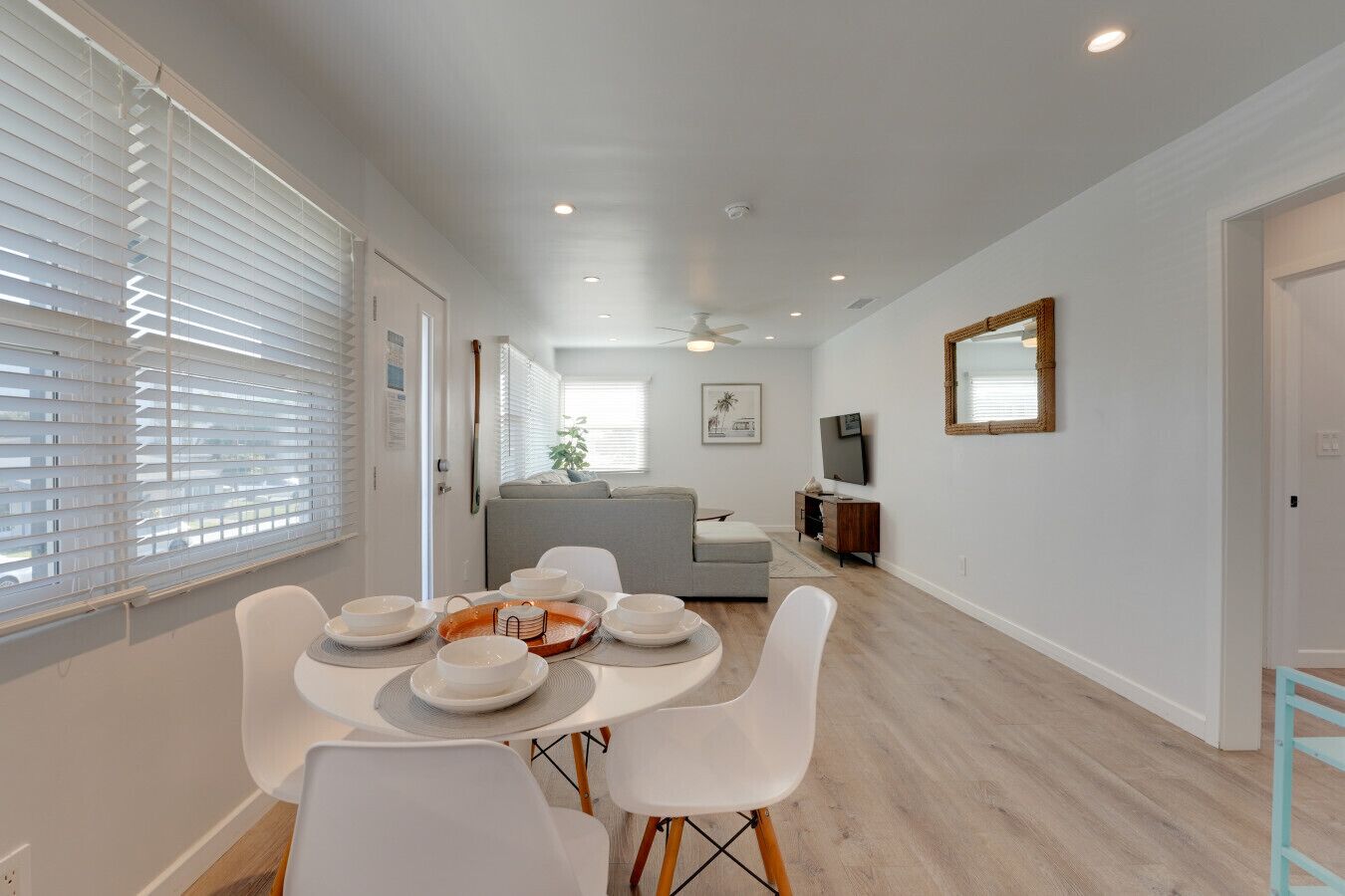 A modern living room with a dining area, a grey sofa, a TV, and a ceiling fan.