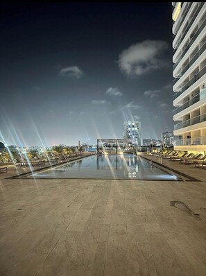 A rooftop pool area with lounge chairs and a modern building in the background. - Cartagena Ocean View  Beach Resort & Pool (Cartagena)