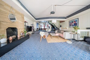 Ein geräumiger Wohnbereich mit Kamin, Treppe und großem Fenster.