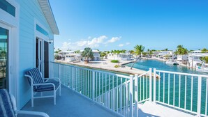 Ein Balkon mit weißen Geländern mit Blick auf einen Yachthafen mit Booten und Palmen.