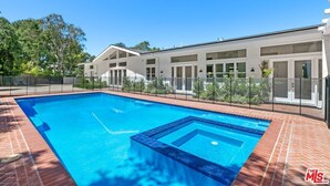 A swimming pool with a rectangular shape and a small hot tub in the center, surrounded by a brick deck.