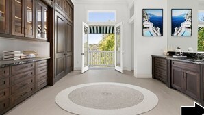 A spacious kitchen with dark wooden cabinets, a round rug, and a view to a balcony.