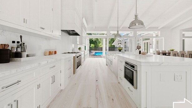 A spacious kitchen with white cabinetry, a large island, and pendant lighting.