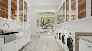 A laundry room with a sink, washing machines, and cabinets.
