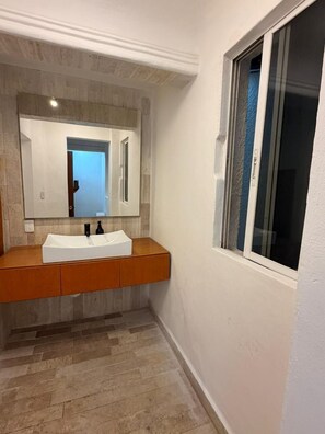 A bathroom with a white sink, wooden vanity, and a large mirror. - Suites Luna y Sol Caribe (Cancún)