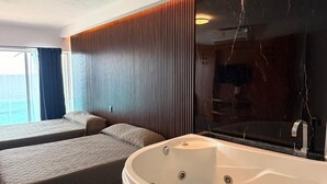 A modern room with a large bathtub, two beds, and a view of the sea. - Suites Luna y Sol Caribe (Cancún)