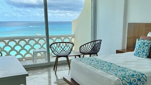 A hotel room with a balcony, a bed, two chairs, and a table. - Suites Luna y Sol Caribe (Cancún)