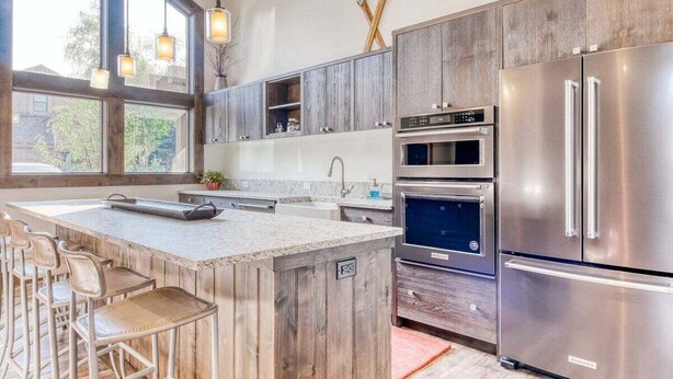 Una cucina moderna con mobili in legno, elettrodomestici in acciaio inossidabile e un'area bar con sgabelli.