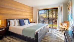 Camera da letto moderna con un letto grande, pareti in legno, vista all'esterno e una scrivania con sedia.