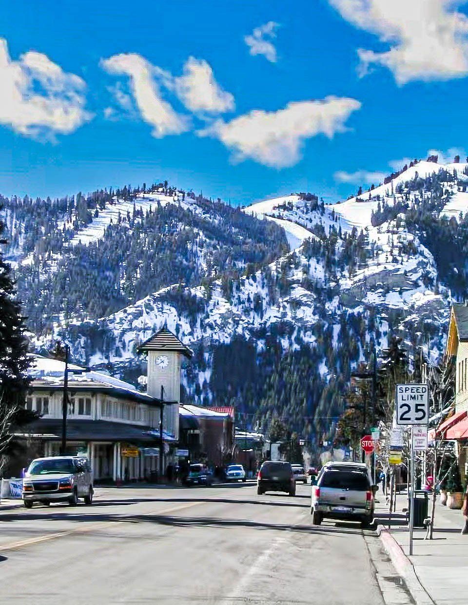 Une ville dotée d’un beffroi, d’un panneau indiquant la limite de vitesse et dont le paysage est dominé par des montagnes.