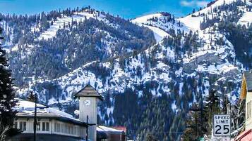 Une ville dotée d’un beffroi, d’un panneau indiquant la limite de vitesse et dont le paysage est dominé par des montagnes.