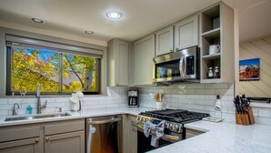 A modern kitchen with grey cabinets, a stainless steel dishwasher, a gas stove, and a microwave. - Ridge Condo - Luxury Condo w/Resort Amenities (Sun Valley)