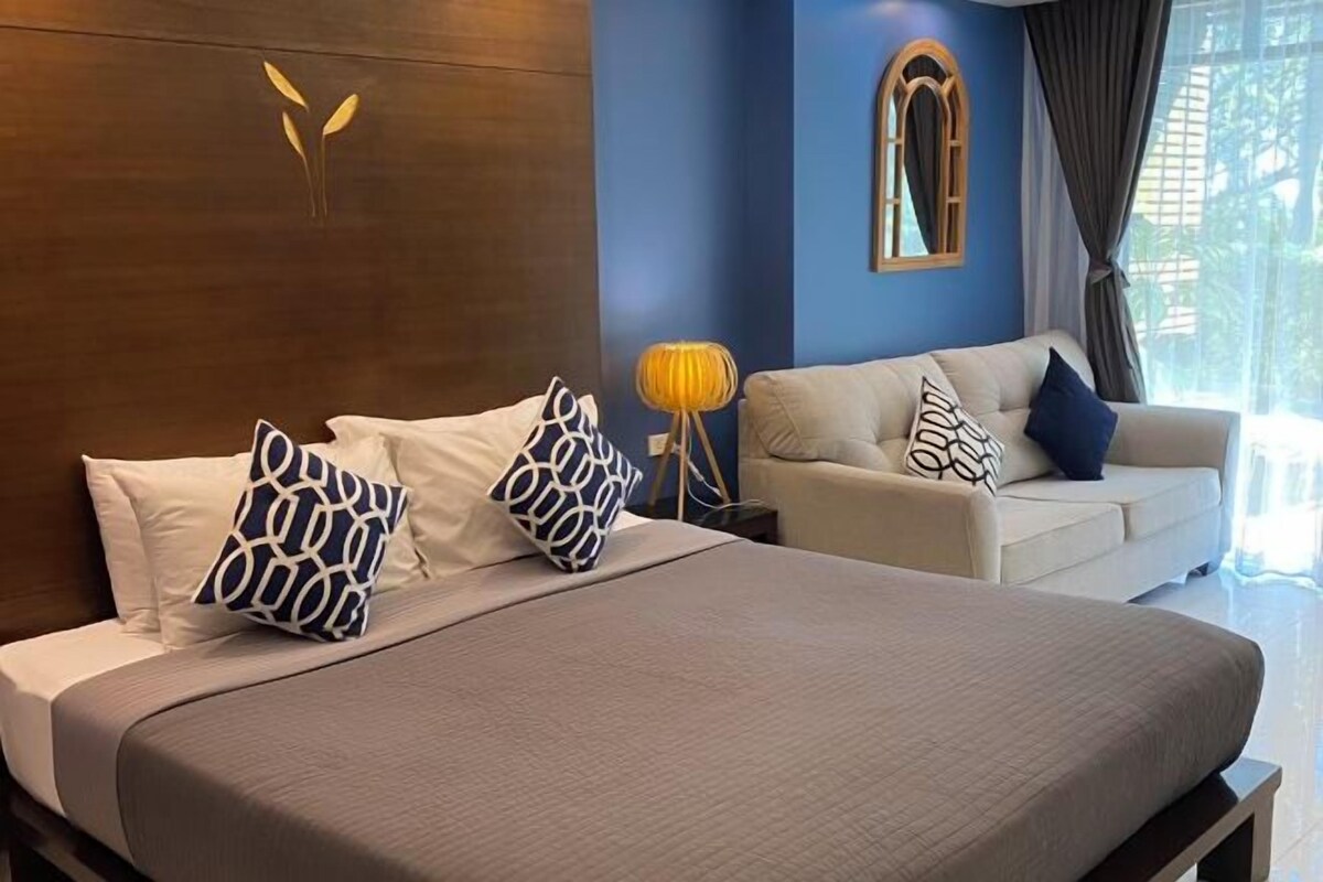 A hotel room with a bed, a sofa, and a nightstand.