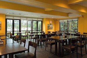 A conference room with multiple tables and chairs, large windows with blinds, and a painting on the wall. - The Bihai Hua Hin (Hua Hin)