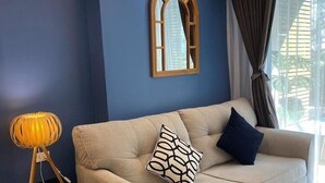 Un salon moderne avec un canapé beige, un miroir à cadre en bois et un lampadaire.