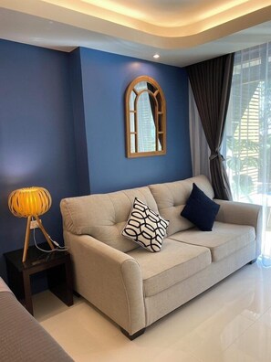 A modern living room with a beige sofa, a wooden-framed mirror, and a floor lamp. - The Bihai Hua Hin (Hua Hin)