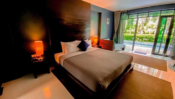 A modern hotel room with a large bed, two bedside lamps, a view of greenery through the window, and a balcony. - The Bihai Hua Hin (Hua Hin)